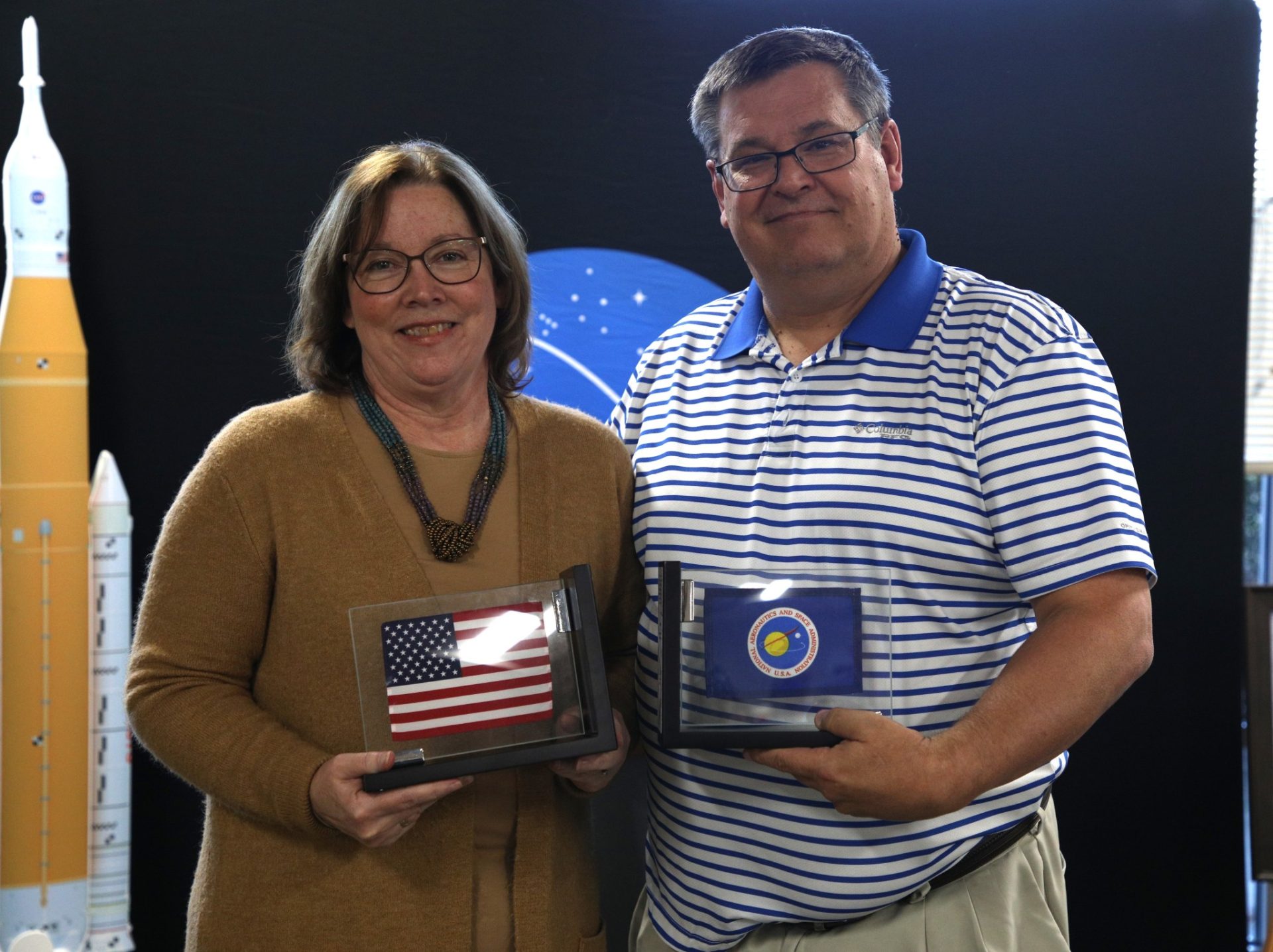 NASA’s Marshall Space Flight Center Associate Director, Technical, Larry Leopard, right, presents Mary Beth Koelbl with bookends for her retirement. Encapsulated in them are flags that were flown in space