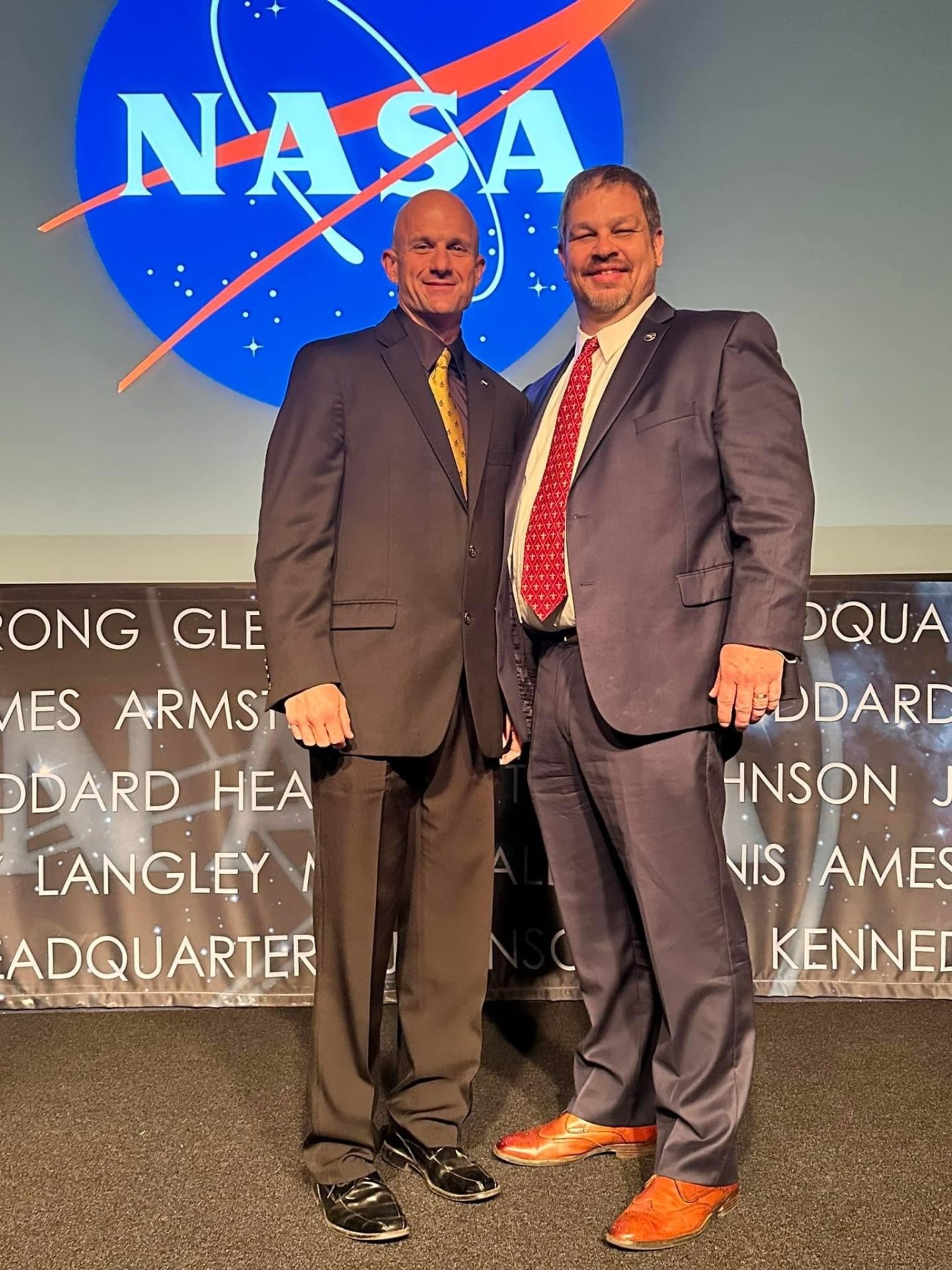 Eli Ouder, left, and Thom Rich are pictured at NASA Headquarters; The NASA insignia is visible in the background