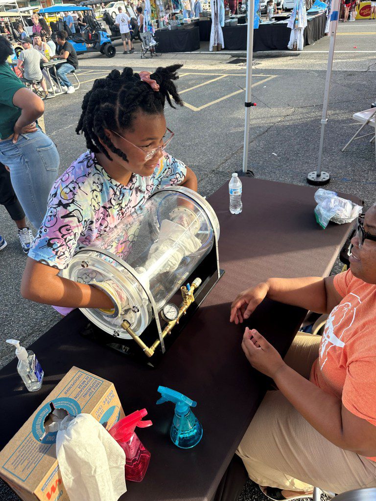 A NASA Stennis representative engages with a member of the Artemis Generation at the Picayune Street Fair